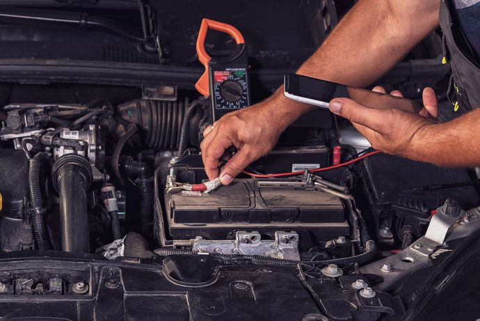 Un meccanico utilizza i cavi di avviamento per far partire la batteria di un'auto nel vano motore.