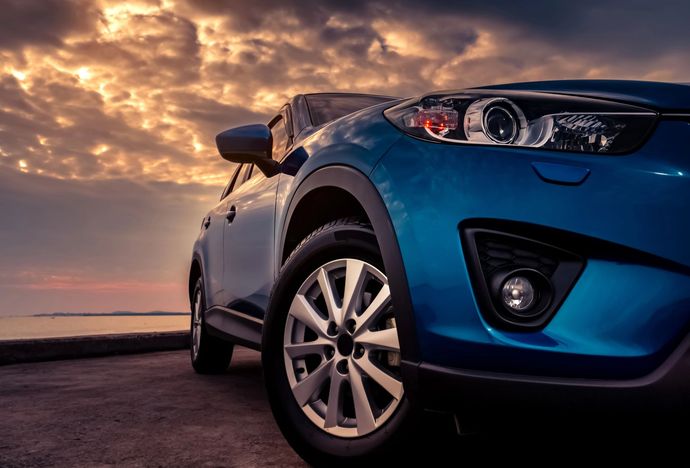 Un'auto blu parcheggiata sotto un cielo al tramonto spettacolare