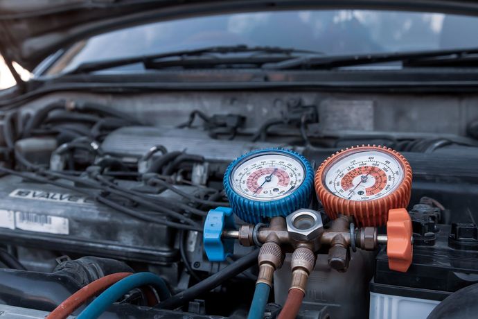 Manometri blu e arancioni per il collettore dell'aria condizionata collegati alle porte di servizio del motore dell'auto sotto il cofano