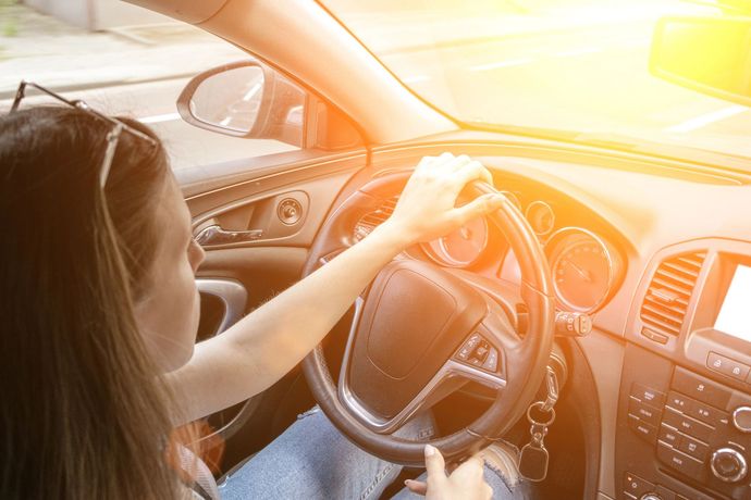 Il conducente tiene il volante nell'abitacolo illuminato dal sole.