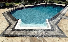 Swimming pool with multi-toned stone patio and entry steps.