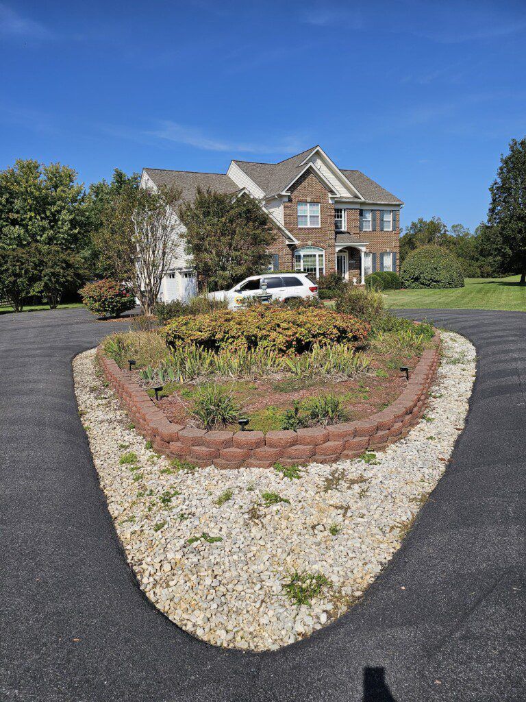 A large house with a circular driveway and a planted center island. Sunny day.
