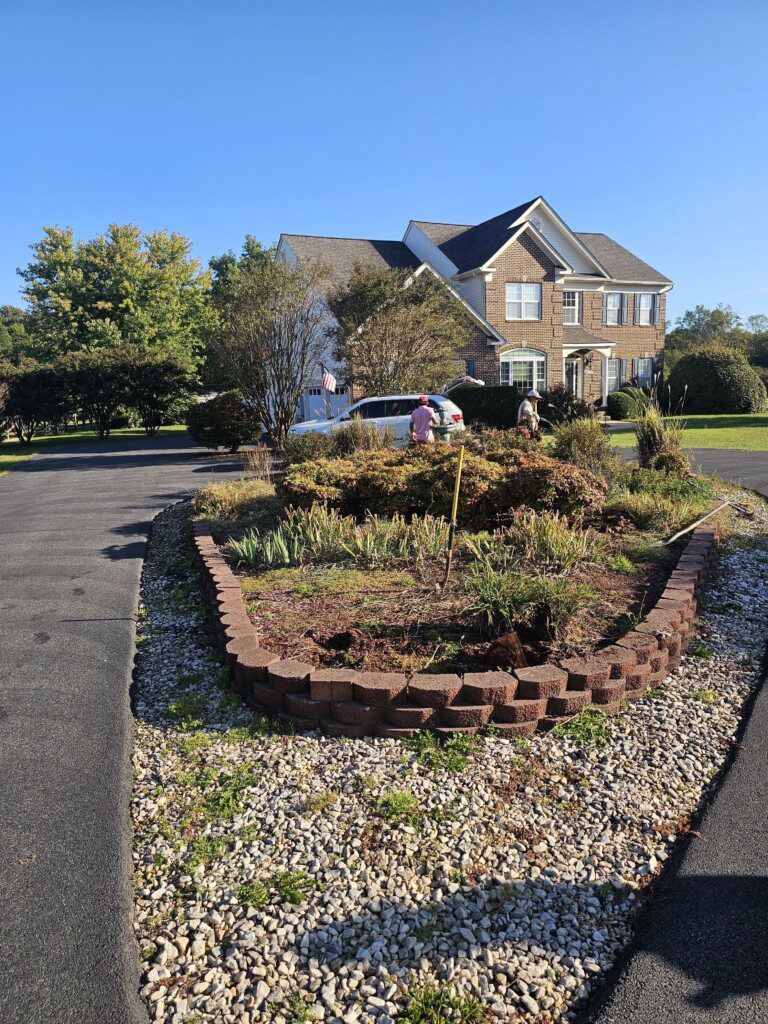 A house with a large circular garden bed in the driveway. The bed has brick edging and gravel.