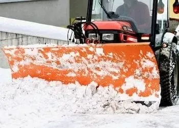 Orange snowplow clearing snow from a road.