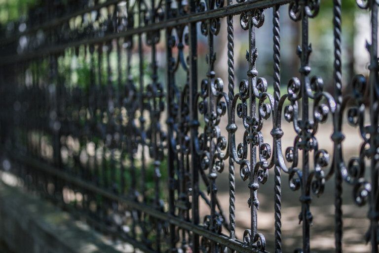 Black wrought iron fence with ornamental scrollwork.
