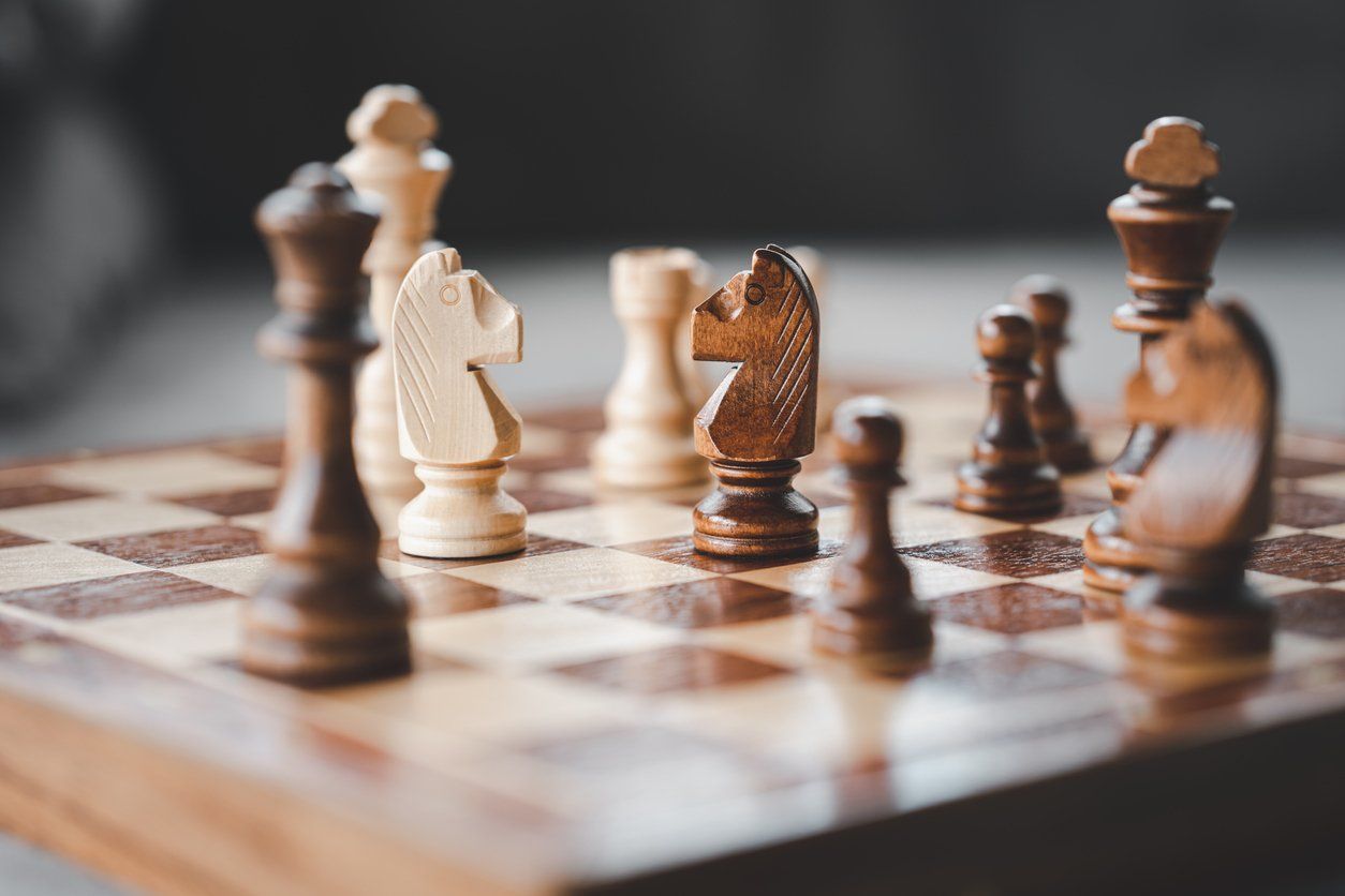 Chessboard with black and white wooden pieces in a mid-game configuration.