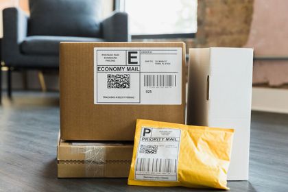 Three packages and a padded envelope on a floor, with shipping labels visible