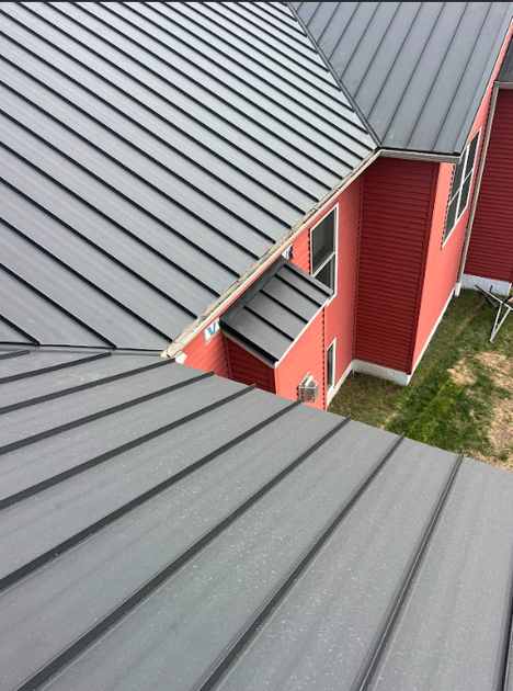 A high-angle view of a gray metal roof on a building with red siding.