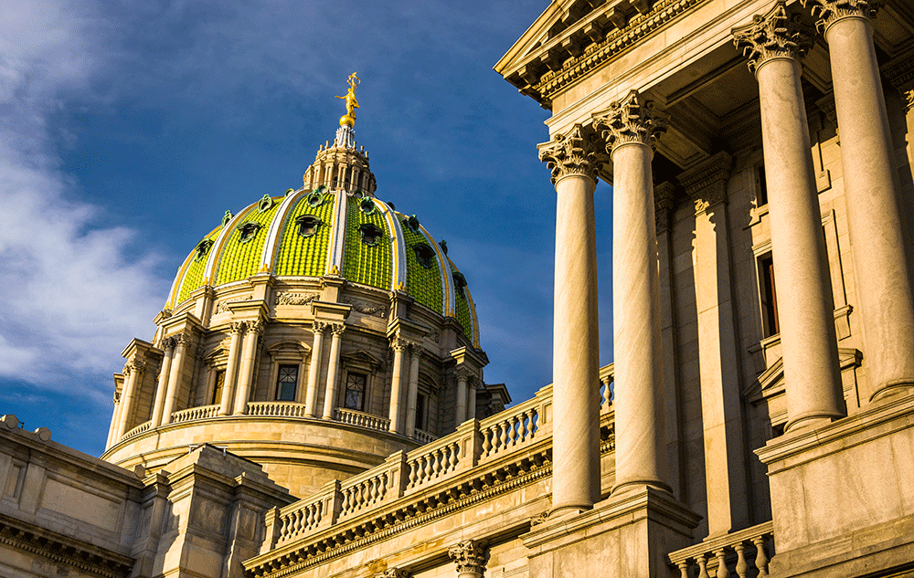 Green-domed historic building with tall stone columns against a blue sky