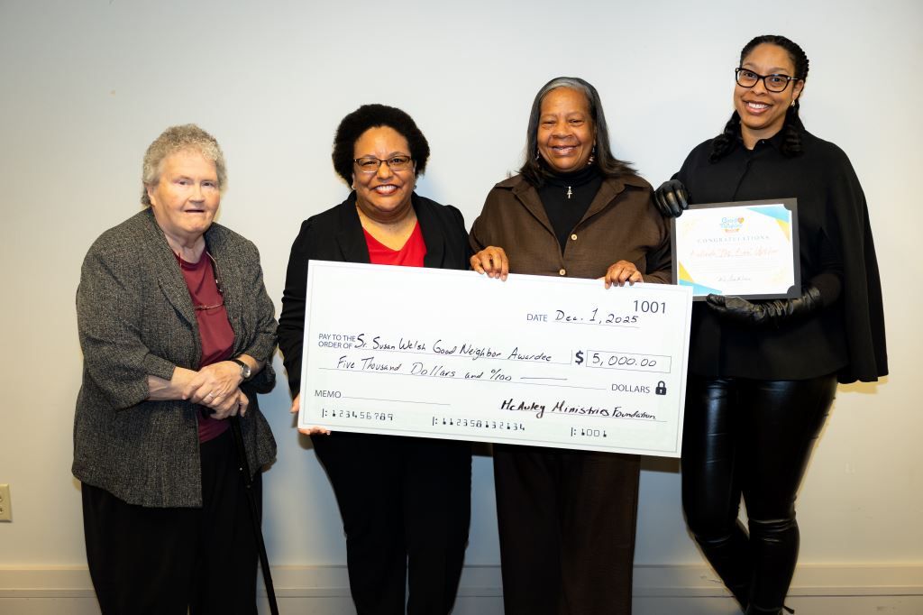 Four women in suits holding a large check and certificate.