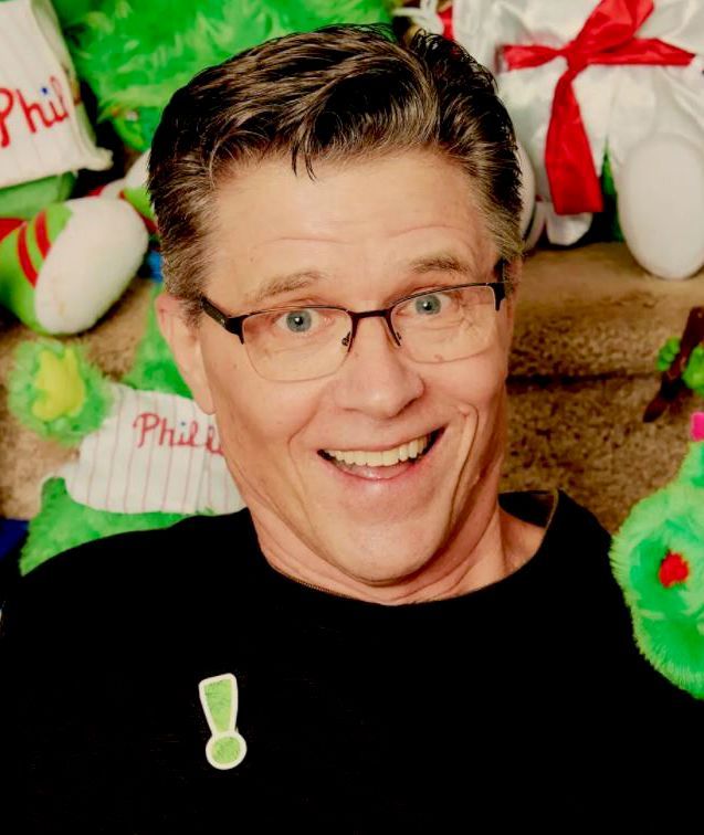 Keynote Presenter Name Smiling man with glasses in front of festive holiday plush decorations