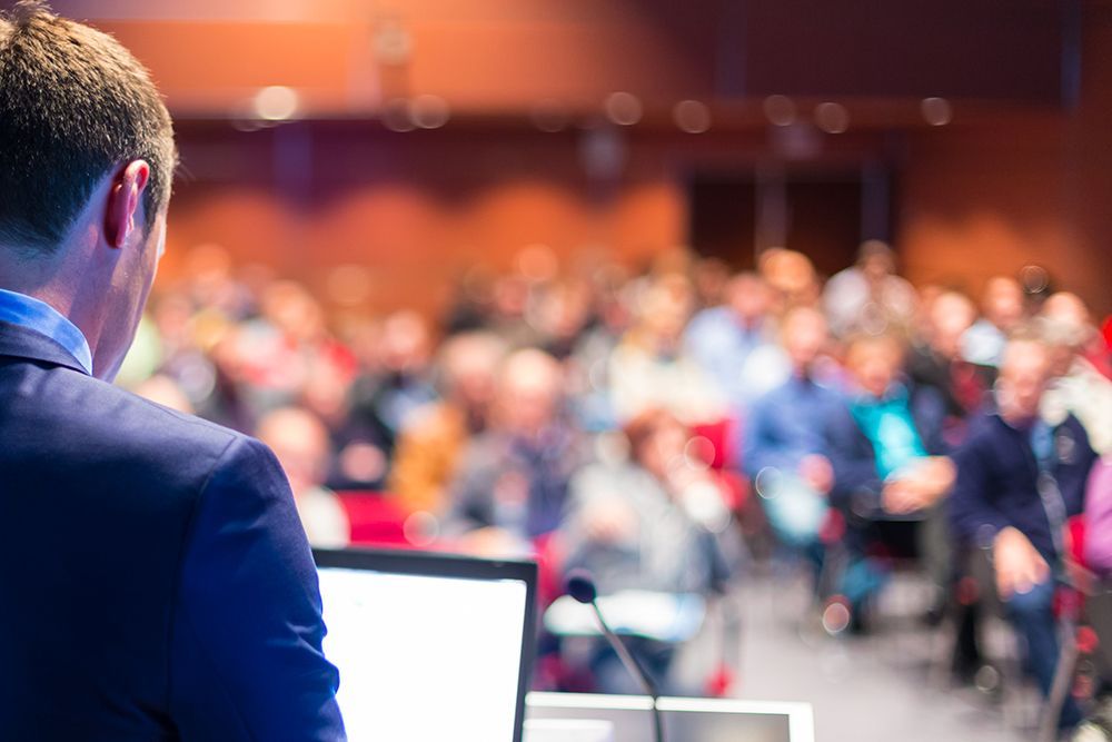 Man in suit presenting to an audience from behind a podium