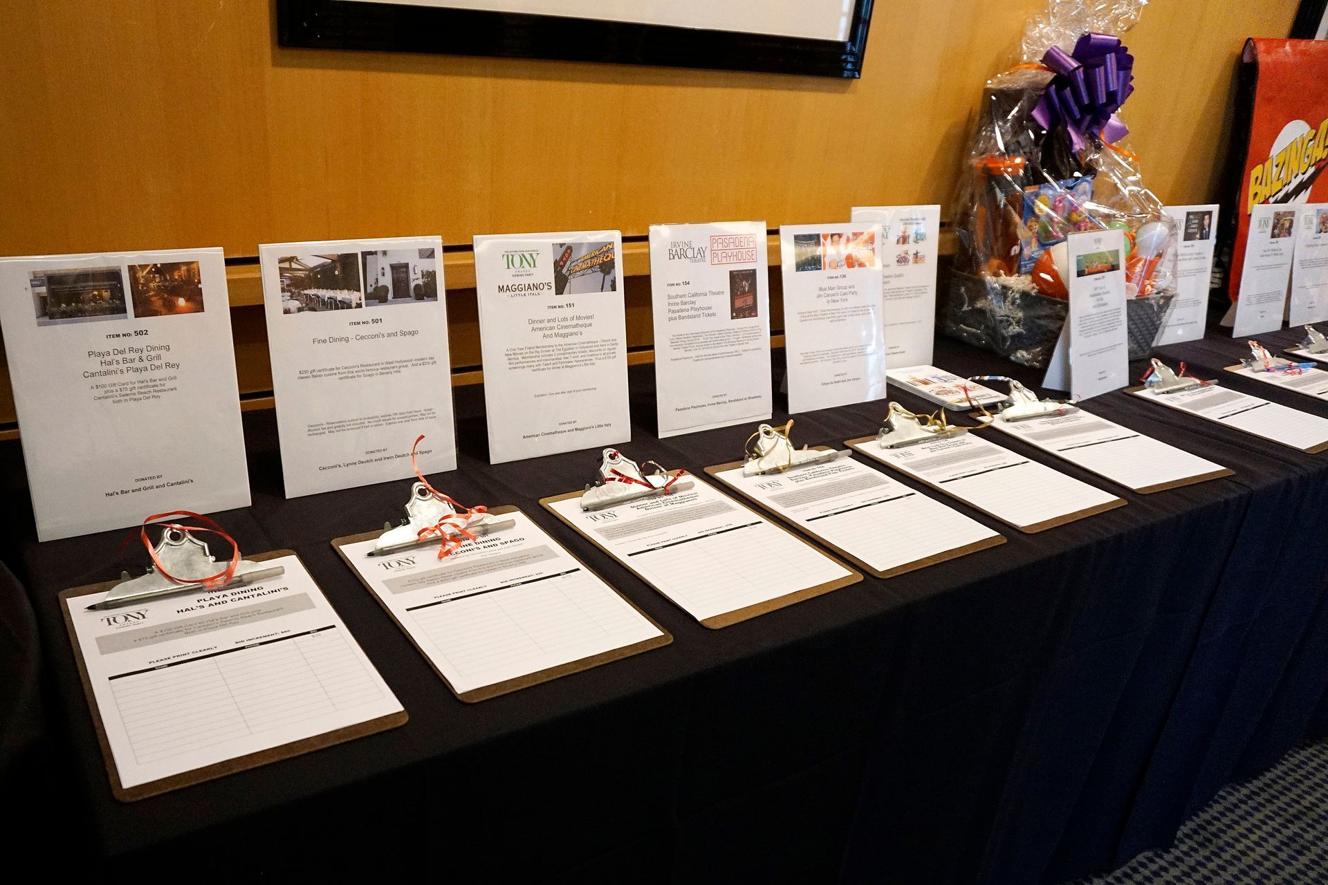 Table of displayed auction bids with placards and a gift basket on the right