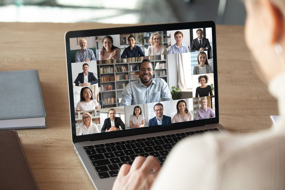 Person attending an online conference on laptop, with many attendees' faces shown