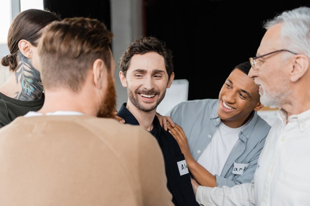 Man surrounded by others who appear supportive at meet-and-greet for mental health