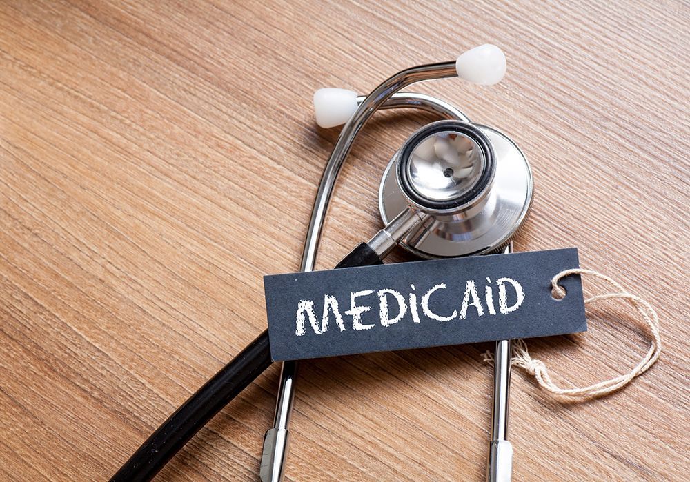 Stethoscope beside a chalkboard label reading “Medicaid” on a wooden table