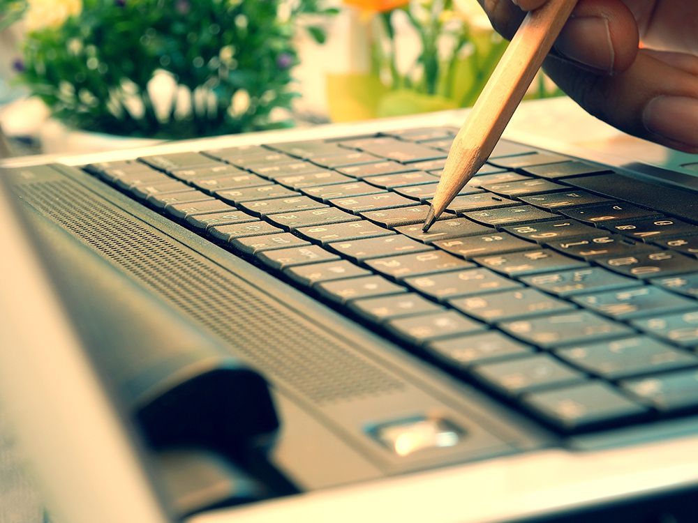 Person using pencil to type a key on the keyboard
