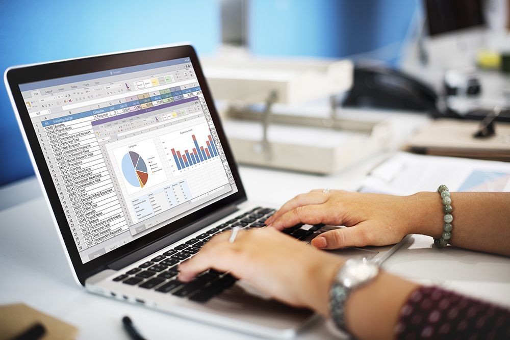 Person typing on laptop with screen showing pie and bar graphs