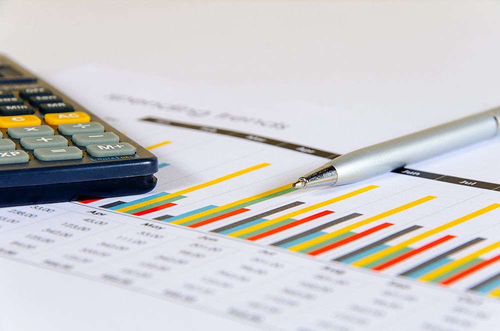 Calculator and pen on top of bar graph paperwork