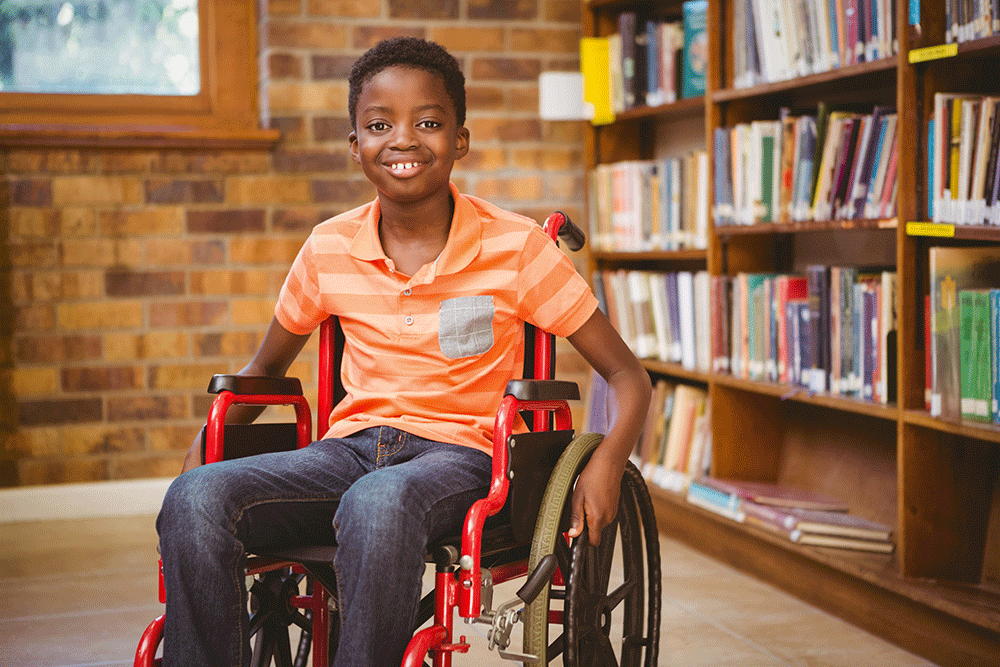 Black kid in a wheelchair smiling at the camera