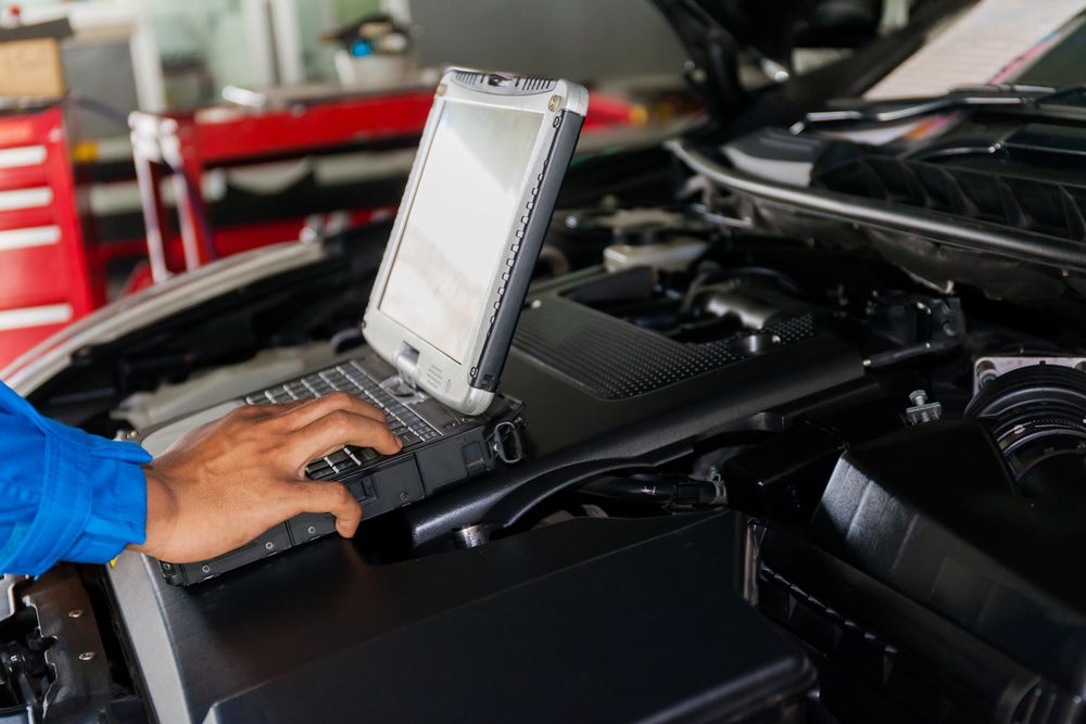 A person is using a laptop computer under the hood of a car — North Queensland Diesel Tune In Kirwan, QLD