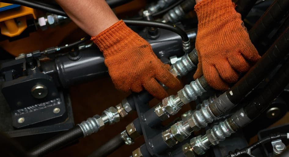 A Person Wearing Orange Gloves Is Working On Hydraulic Hoses — North Queensland Diesel Tune In Kirwan, QLD