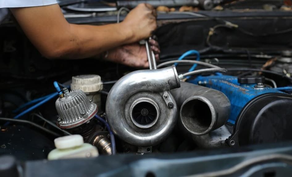 A Man Is Working On A Car Engine With A Wrench — North Queensland Diesel Tune In Kirwan, QLD