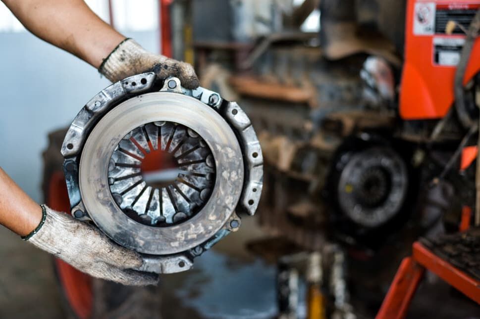 A Person Is Holding A Clutch Plate In Their Hands In A Garage — North Queensland Diesel Tune In Kirwan, QLD
