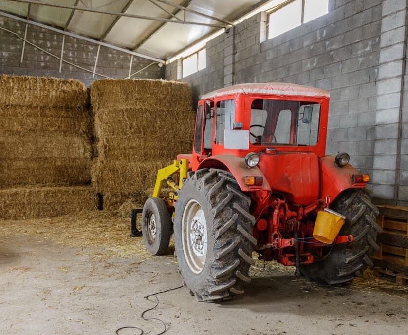 A Red Tractor Is Parked In A Barn With Hay Bales — North Queensland Diesel Tune In Kirwan, QLD