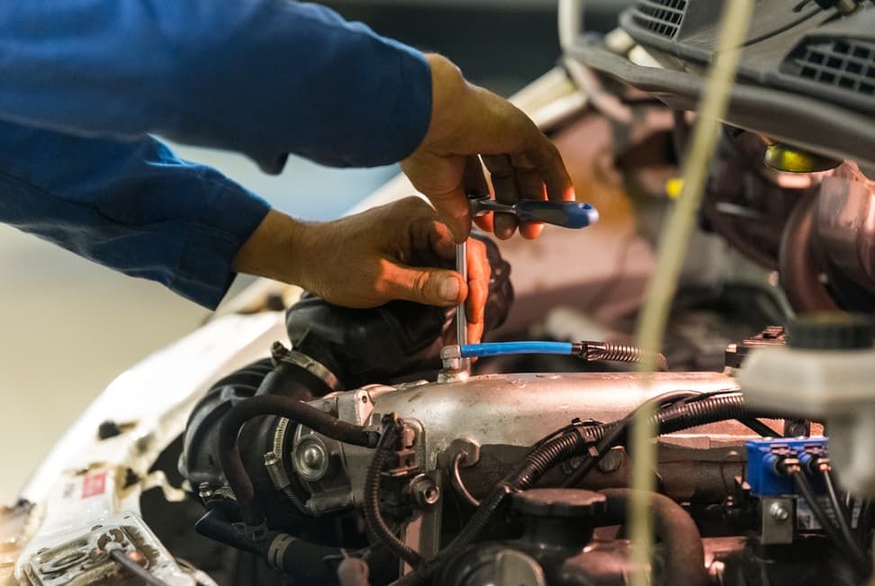 A Man Is Working On A Car Engine With A Screw — North Queensland Diesel Tune In Kirwan, QLD