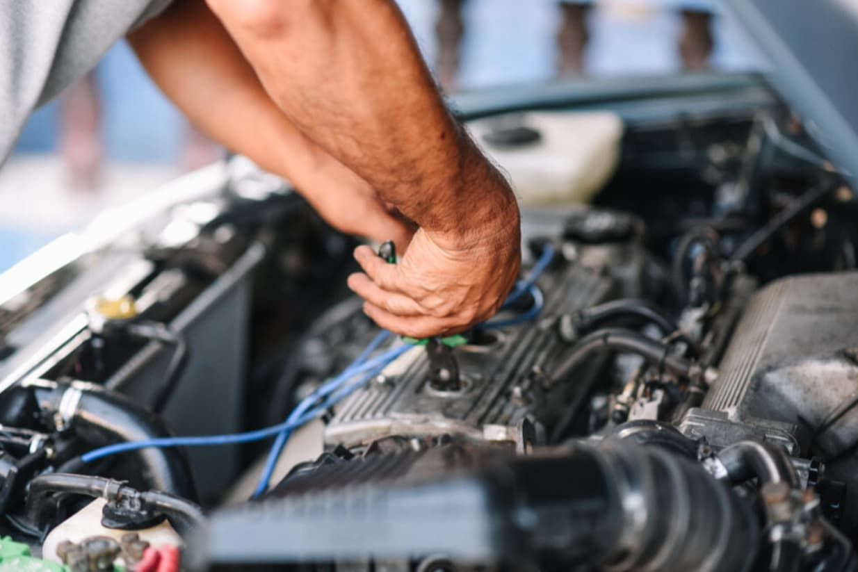 A Man Is Working On A Car Engine With A Screwdriver — North Queensland Diesel Tune In Kirwan, QLD