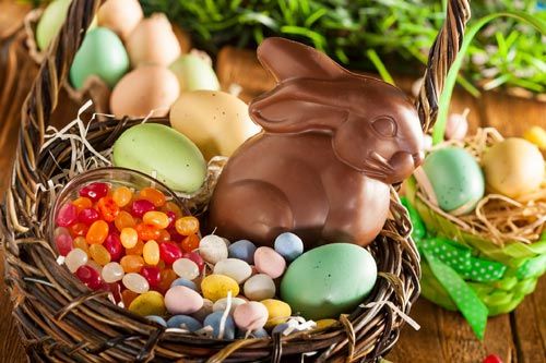 Easter baskets filled with colorful eggs, jelly beans, and a chocolate bunny, on a rustic wooden surface.
