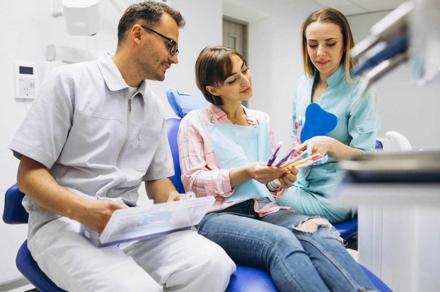 Dentist and assistant showing a patient teeth whitening shade options in a dental office.