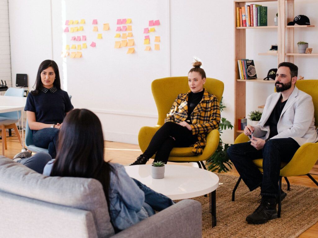 A group of people are sitting around a table in a living room.