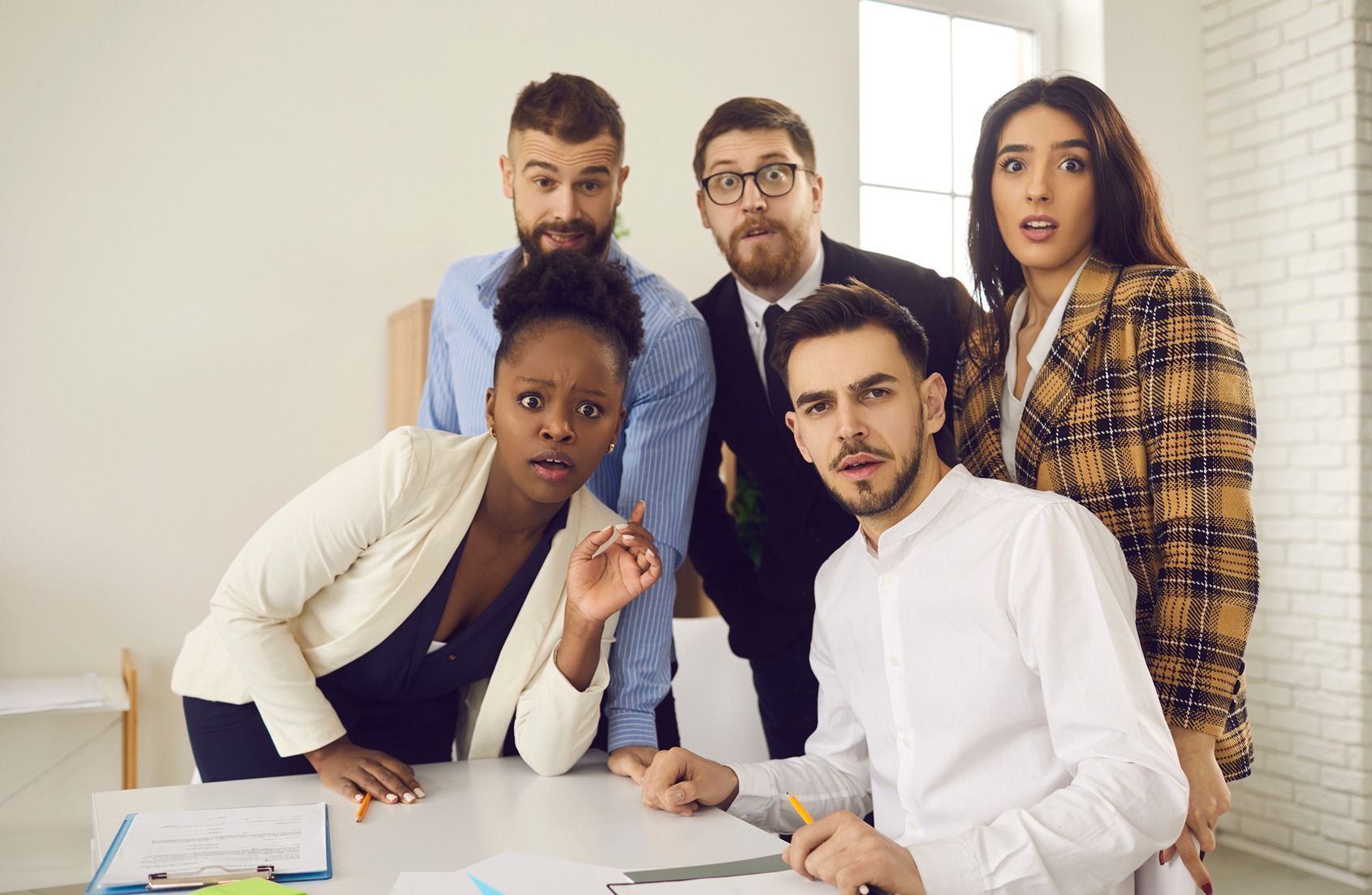 A group of people are standing around a table in an office.