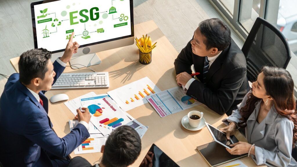A group of business people are sitting around a table looking at a computer screen.