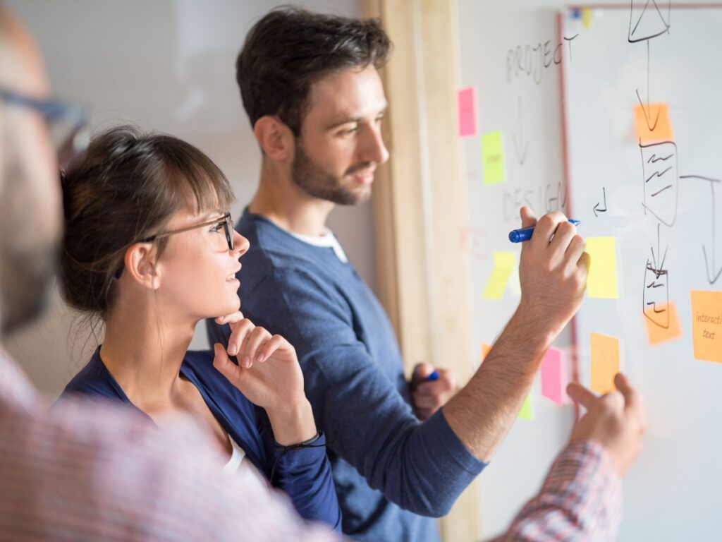 A man is writing on a whiteboard with sticky notes.
