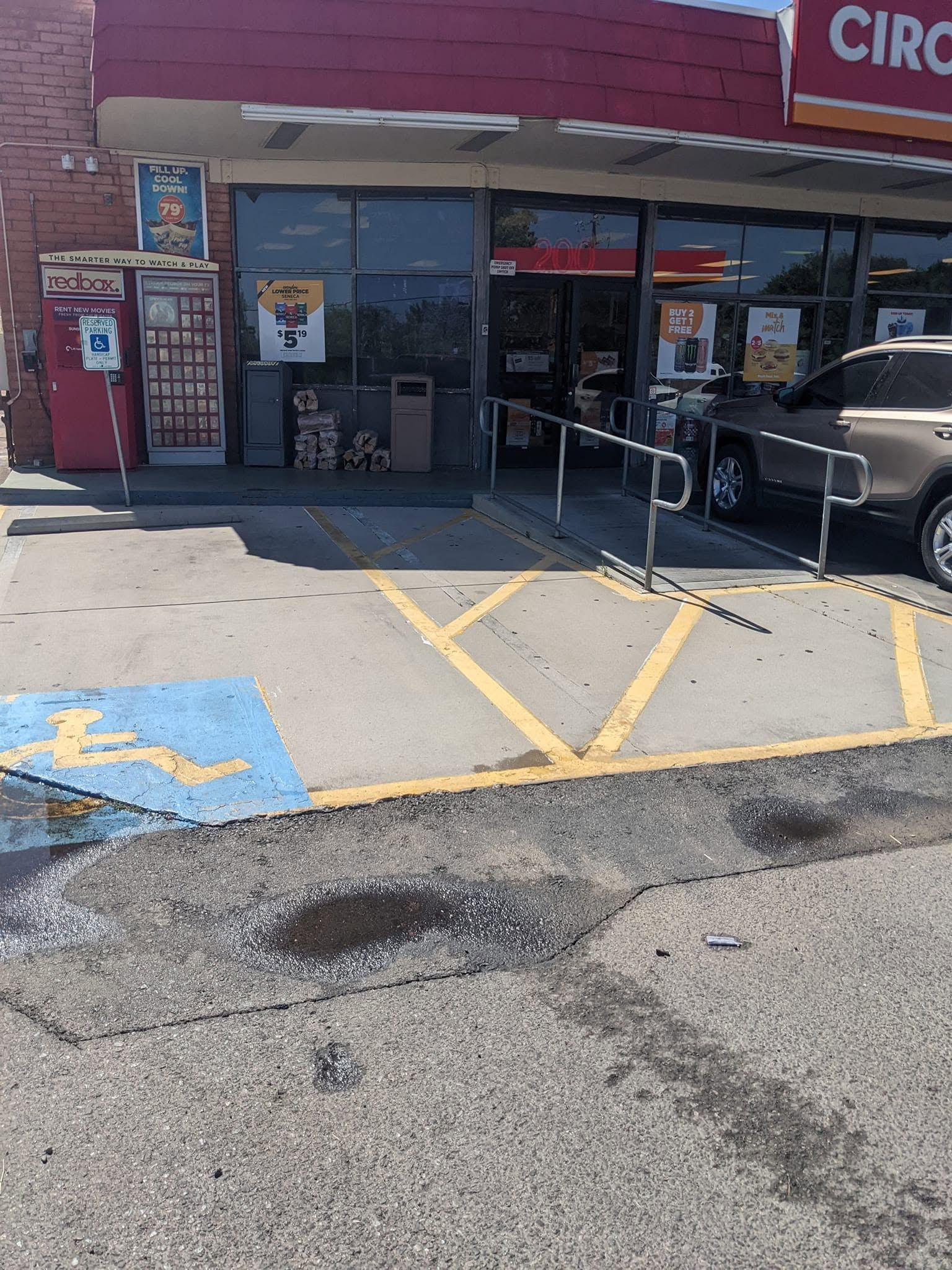 Storefront with accessible parking spaces and a ramp, with a black SUV parked by the entrance.