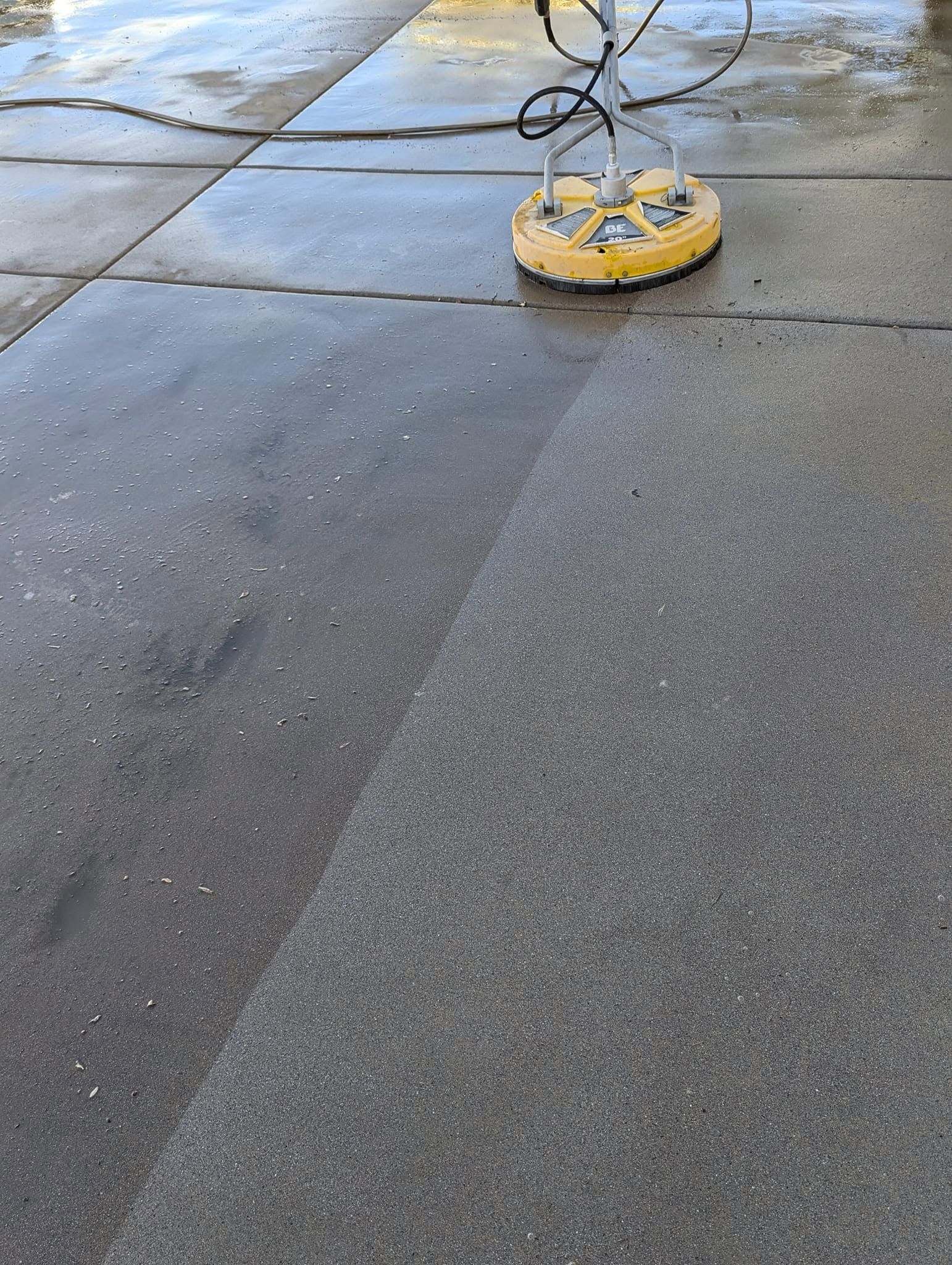 Yellow power tool on wet concrete pavement with cables nearby
