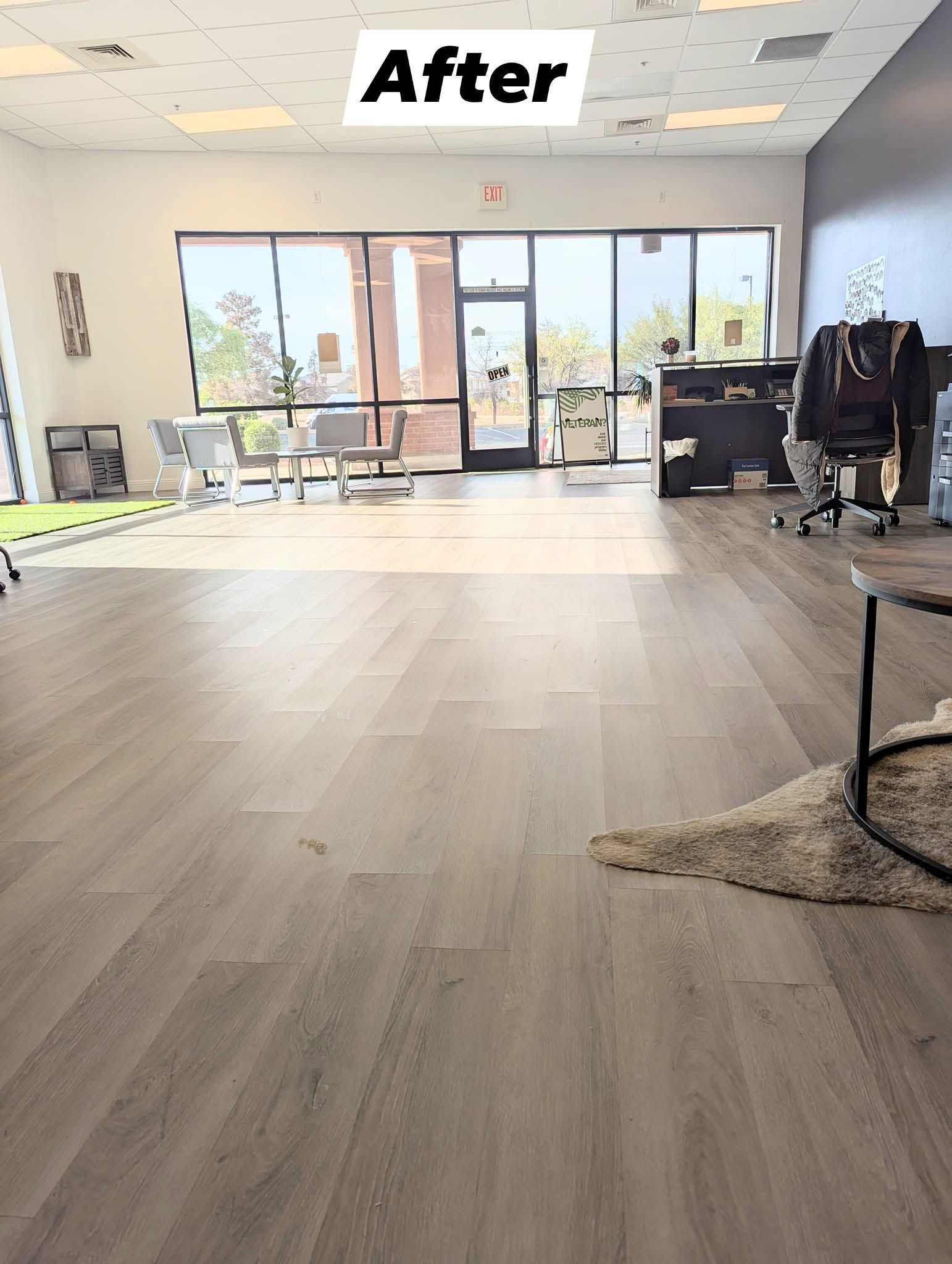 Empty retail storefront with wood-look floor, glass doors, and an