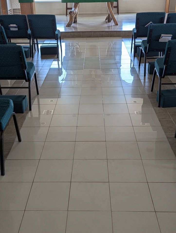 Empty waiting area with rows of dark chairs and a tiled floor leading to a doorway.