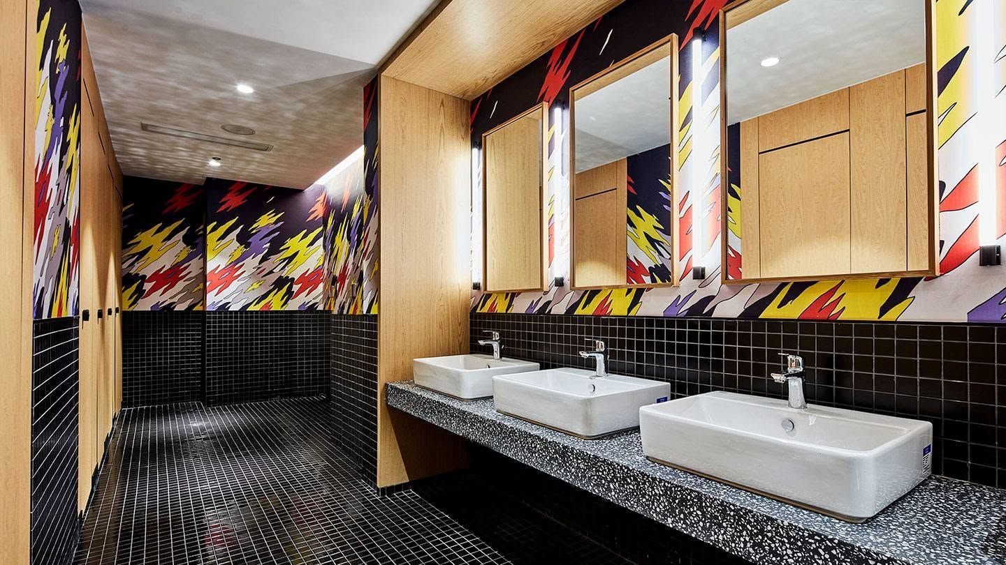 Modern restroom with black countertops, white sinks, mirrors, and bold colorful wall art