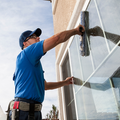 Worker in blue shirt cleaning a building window with a squeegee