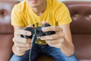 Person in a yellow shirt holding a game controller on a couch