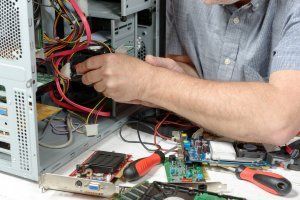 Technician repairing a desktop computer with tools and exposed internal components on a workbench
