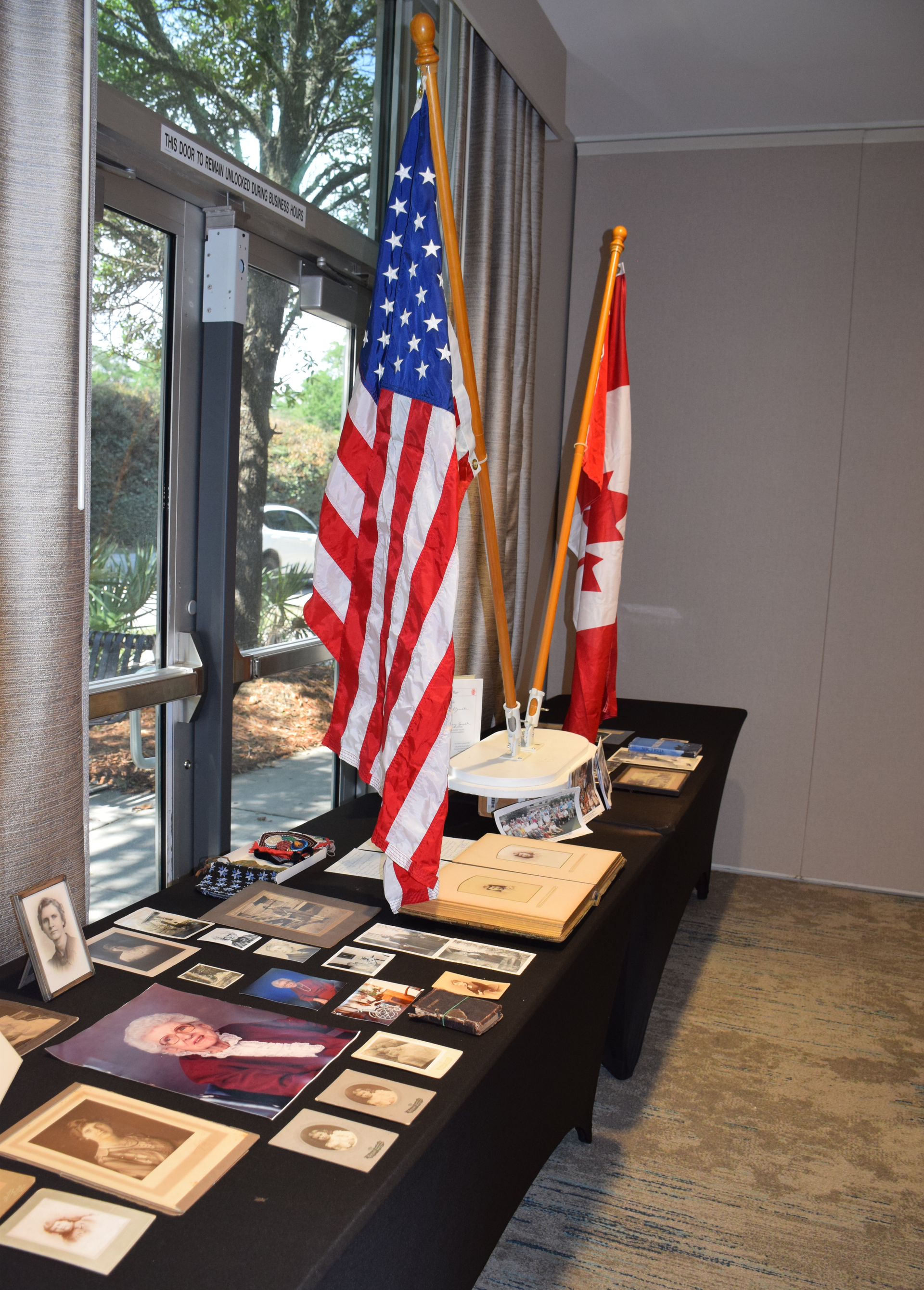 Table with American and Canadian flags, historical photos, and objects displayed in a room.