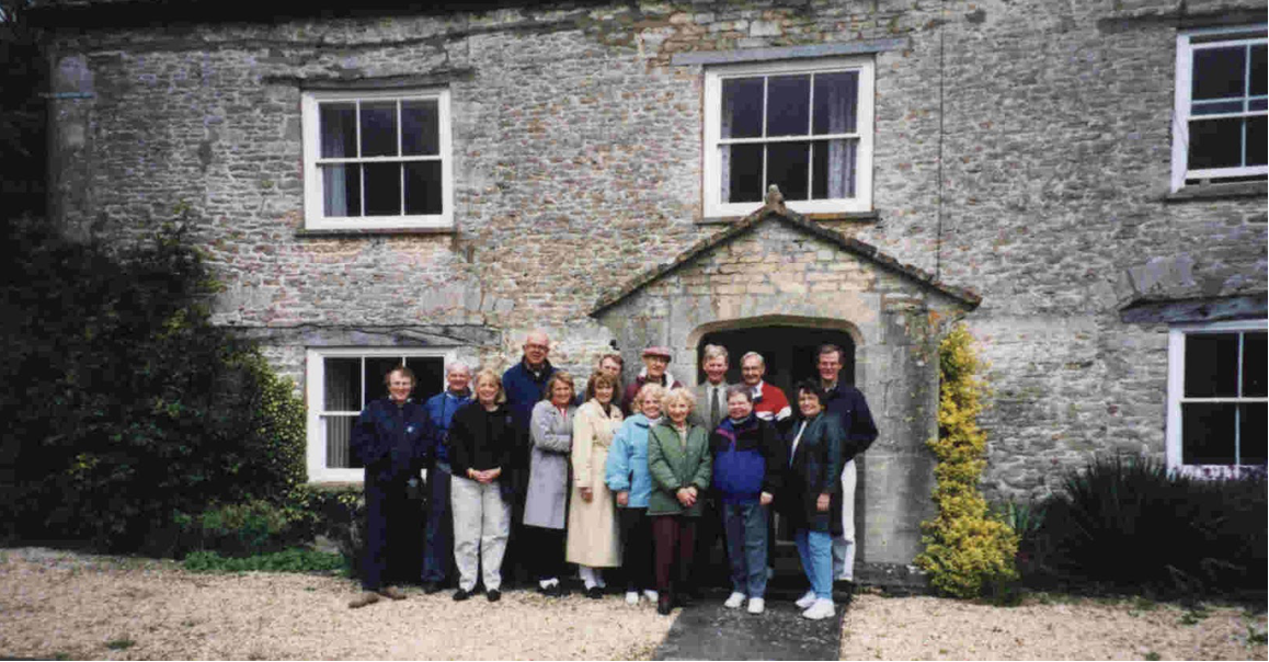 A group of people are standing in front of a large stone building.
