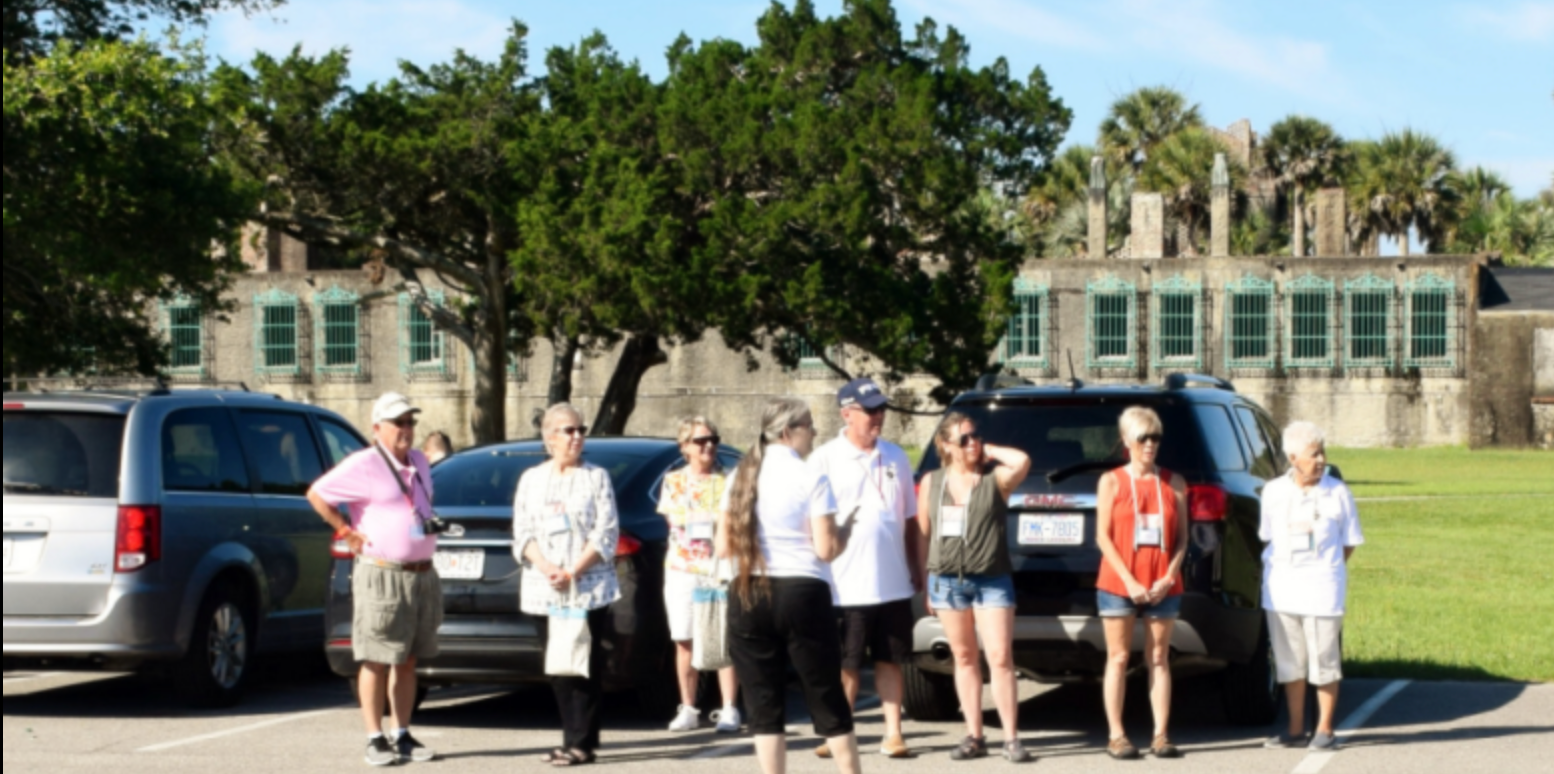 A group of people are standing in a parking lot in front of a building