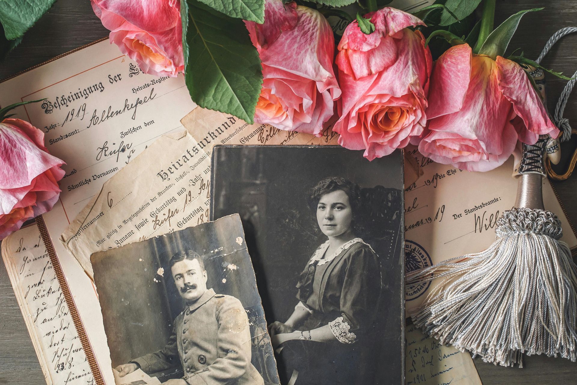A black and white photo of a man and woman sitting next to pink roses.