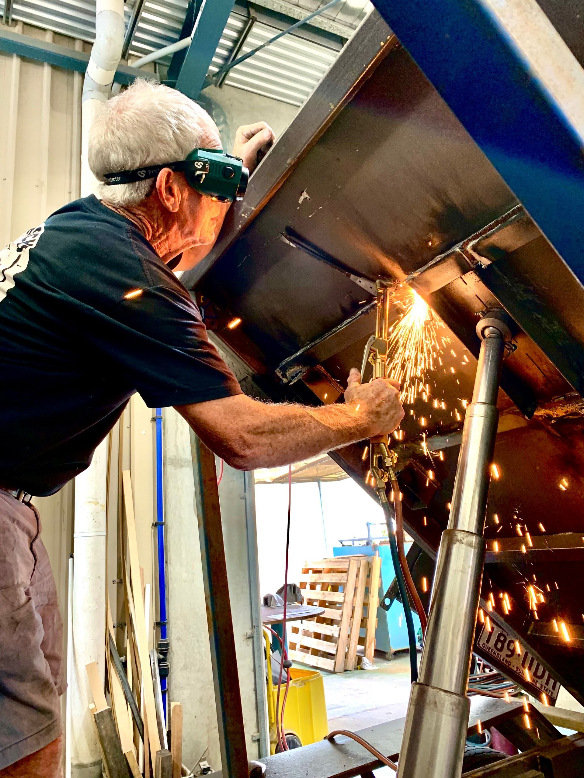 A man is welding a piece of metal in a factory.
